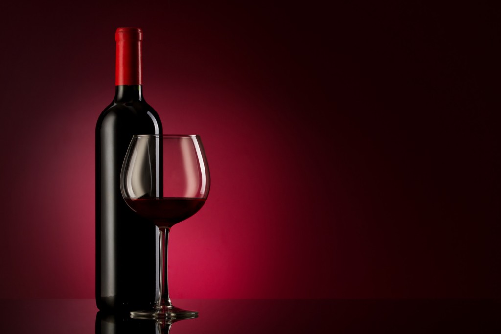 bottle with red wine and glass on a red gradient