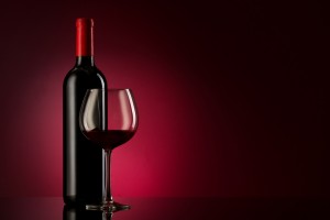 bottle with red wine and glass on a red gradient