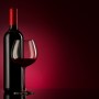 bottle with red wine and glass on a red gradient